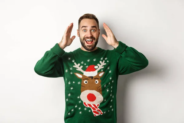 Noel, tatiller ve kutlamalar. Şaşırmış bir adam gözlerini açar ve beyaz arka planda mutlu duran bir hediye görür. — Stok fotoğraf