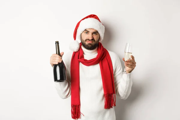 Festa de Natal e conceito feriados. Homem barbudo cético em Santa chapéu e cachecol, segurando champanhe e reclamando, de pé contra fundo branco — Fotografia de Stock