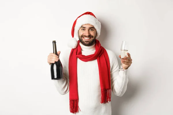 Julfest och helgkoncept. Glad skäggig man i Santa hatt, fira nyår, dricka champagne, står över vit bakgrund — Stockfoto