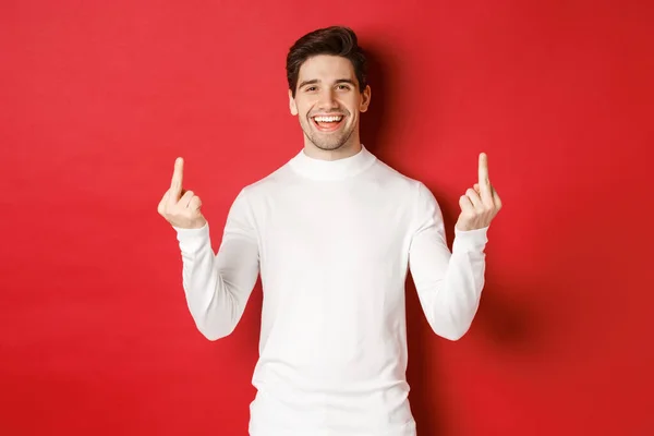 Image of rude and unbothered man laughing while showing middle-fingers, telling to fuck-off, standing over red background — Fotografia de Stock