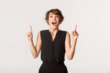 Heyecanlı ve şaşırmış genç bir kadın pankarta bakıp işaret ediyor.