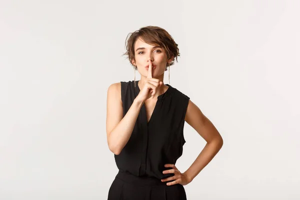 Retrato de mujer atractiva coqueta ocultando secreto, callando a la cámara con el dedo presionado a los labios, fondo blanco — Foto de Stock
