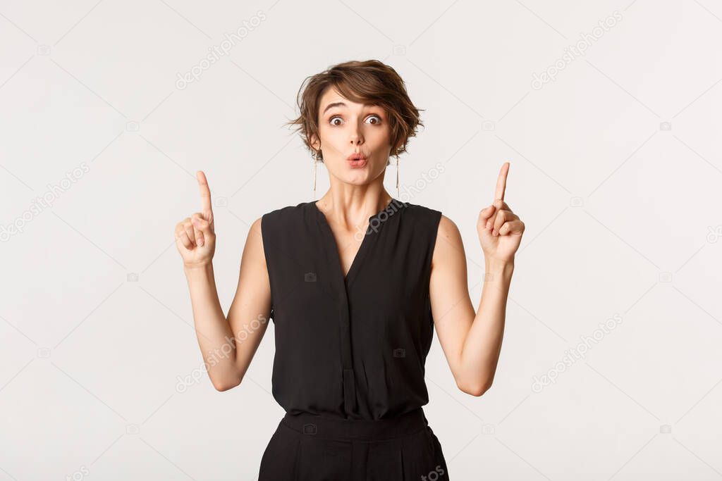 Image of surprised attractive woman looking impressed, pointing fingers up