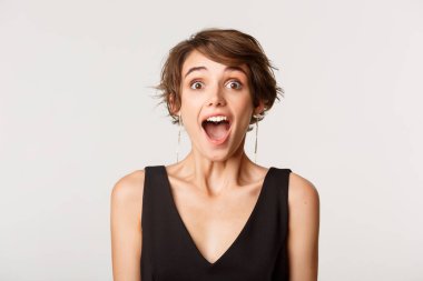 Kendinden geçmiş kızın yakın plan çekimi. Çenesini indir ve kameraya bak. Beyaz arka planda duruyor.