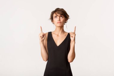 Hayal kırıklığına uğramış siyah elbiseli, üzgün ve yukarı bakan, beyaz arka planda duran