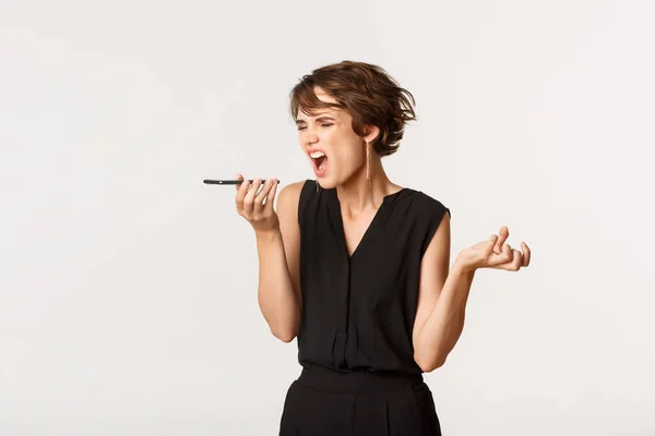 Mulher irritada gritando, gravando mensagem de voz, gritando com alguém por telefone, de pé fundo branco — Fotografia de Stock