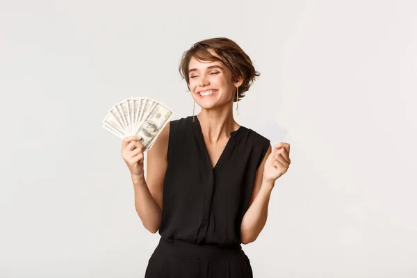 Framgångsrik elegant kvinna ler nöjd, visar pengar och kreditkort — Stockfoto