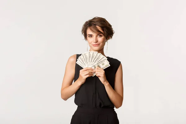 Sassy affärskvinna visar pengar och ler mot kameran, står över vit bakgrund — Stockfoto