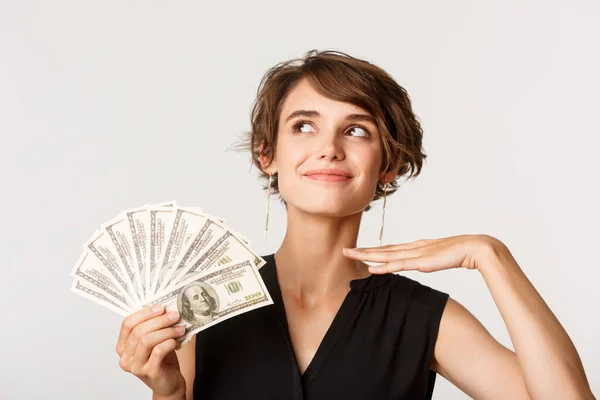 Fashionabla rik elegant kvinna ser kaxig, visar pengar, står över vit bakgrund — Stockfoto