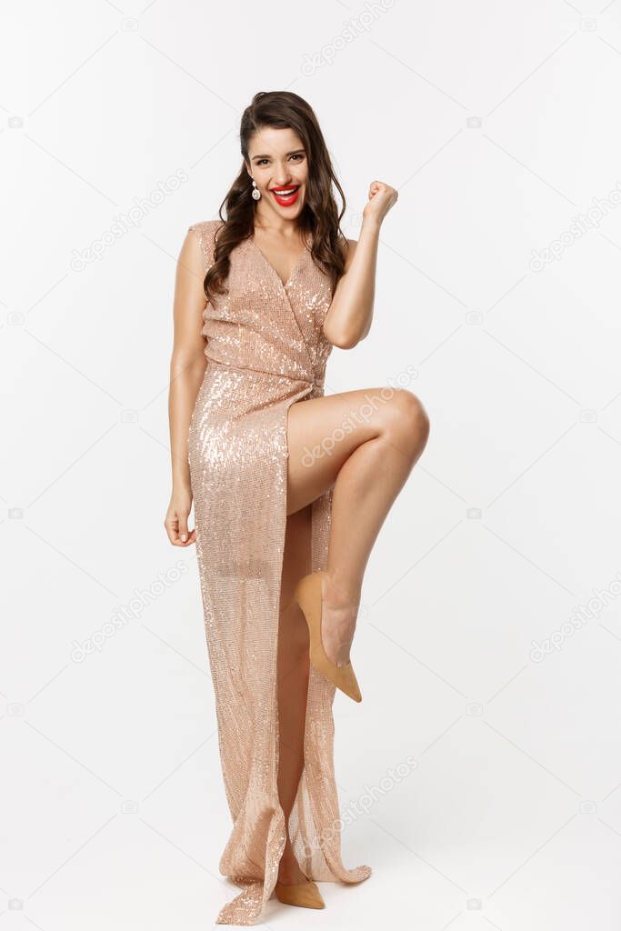 Christmas party and celebration concept. Full length of lucky woman feeling excited, wearing elegant dress, making fist pump and rejoicing, winning