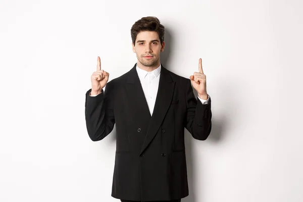 Изображение уверенного и красивого мужчины в официальном костюме, указывающего пальцем вверх, показывающего пространство для копирования на белом фоне — стоковое фото
