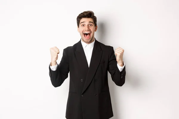 Imagem de homem de negócios feliz e aliviado sentindo-se sortudo, fazendo punho bombas e sorrindo com alegria, alcançar objetivo, ganhar e triunfar, de pé sobre fundo branco — Fotografia de Stock