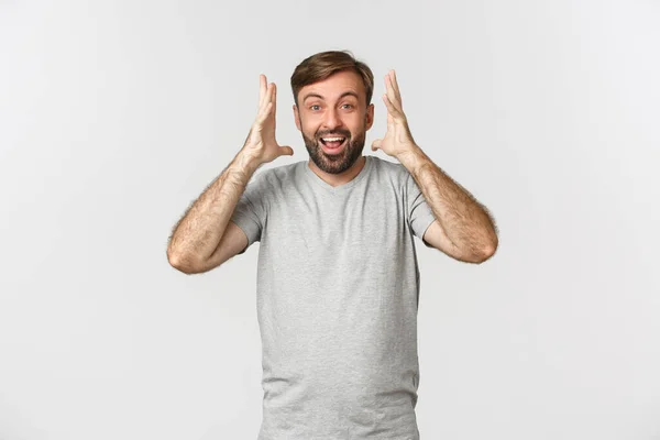 Bild eines aufgeregten, glücklichen Kerls, der erstaunliche Nachrichten hört, vor weißem Hintergrund steht und lächelt — Stockfoto