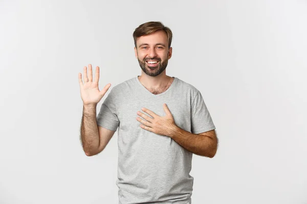 Retrato de cara bonito sincero com barba, fazendo promessa, jurando ou jurando, de pé sobre fundo branco — Fotografia de Stock