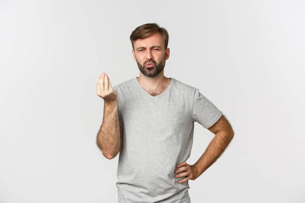 Imagem de belo homem caucasiano mostrando sinal de beijo de chefs e elogiando comida saborosa, bebendo deliciado, de pé sobre fundo branco — Fotografia de Stock