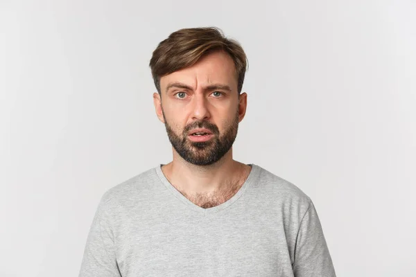 Close-up de cara bonito confuso não pode entender algo, franzindo a testa e olhando perplexo, de pé sobre fundo branco — Fotografia de Stock