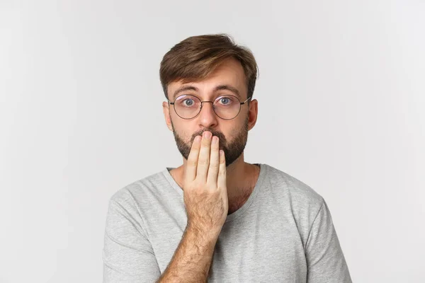 Close-up de homem surpreso em óculos, ofegante e olhando para a câmera em causa, em pé sobre fundo branco — Fotografia de Stock