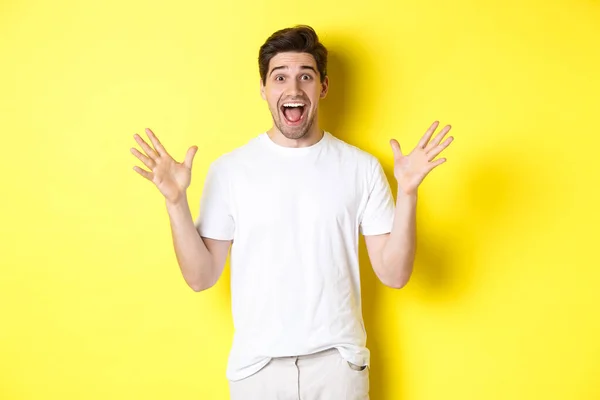 Portret van opgewonden en verraste man reageren op grote promo aanbod, schreeuwen van vreugde en triomferen, staande over gele achtergrond — Stockfoto