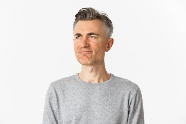 Close-up of disappointed middle-aged man in gray sweater, frowning upset and looking left at copy space, standing over white background — Stock Photo, Image