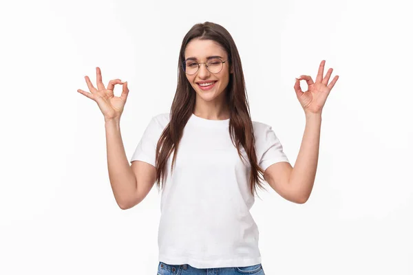 Retrato de cintura hacia arriba de la joven atrevida y segura chica atractiva en gafas, guiño descarado y sonriente tranquilizando todo lo bueno, sin problema, garantizar todo bajo control, sonreír y hacer señales de que está bien — Foto de Stock