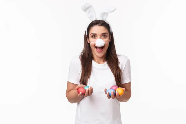 Portrait d'une jeune femme excitée, heureuse et insouciante passant des vacances en famille, portant des oreilles et un nez de lapin drôles, tenant des œufs colorés, le peignant avec des enfants le jour de Pâques, fond blanc — Photo