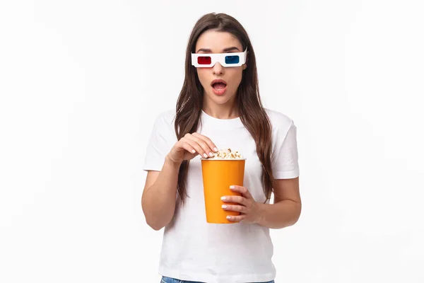 Entretenimiento, diversión y concepto de vacaciones. Retrato de mujer joven asombrada y asombrada mirando interesante emocionado en el cine, disfrutando de la película fresca, comer palomitas de maíz, usar gafas 3d —  Fotos de Stock