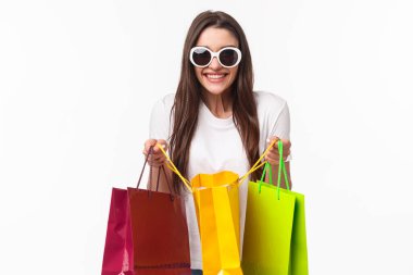 Alışveriş, eğlence ve yaşam tarzı konsepti. Heyecanlı mutlu genç kızın portresi dükkânı sever, en sevdiği alışveriş merkezine gider, bir sürü yeni kıyafet alır, böbürlenir, arkadaşına göstermek için çantasını açar, mutlu bir şekilde gülümser.