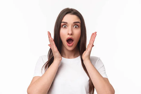 What an amazing news. Surprised and astonished, excited young woman react to something awesome happened, gasping, open mouth and raise hands near face, staring camera, white background — Stock Photo, Image