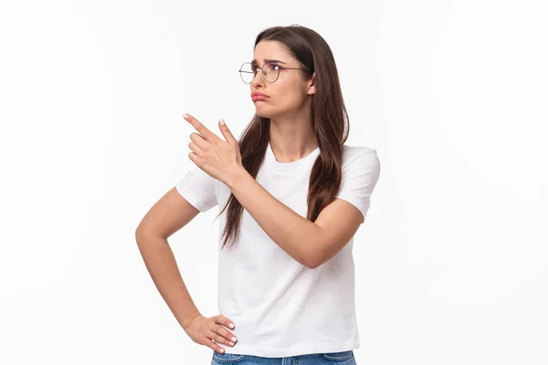 Retrato de la cintura hacia arriba de la piedad o celosa joven morena estudiante perdió gran oportunidad, sentir pesar y emoción incómoda, enfurruñado dolor señalando y mirando esquina superior izquierda —  Fotos de Stock