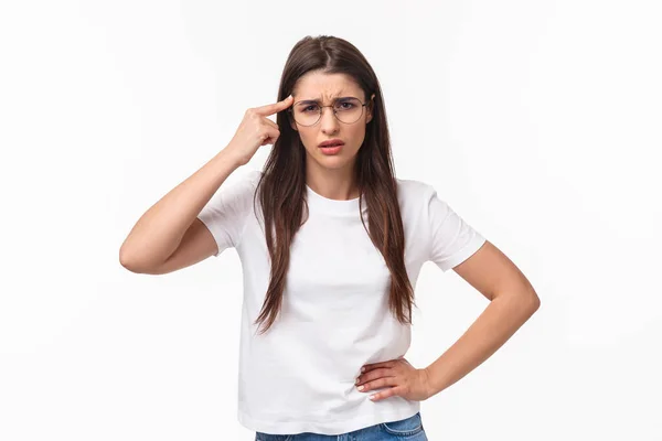 Are you dumb. Portrait of skeptical and bothered, annoyed young woman roll finger over temple and staring with disdain or scorn at person acting crazy, scolding for not thinking before acting — Foto Stock