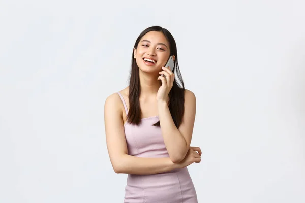 Luxe femmes, fête et vacances concept. Insouciante souriante asiatique femme en robe de soirée parler au téléphone, rire heureux, avoir la conversation sur mobile, fond blanc — Photo