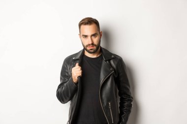 Yakışıklı, sakallı, kendine güvenen, deri ceketine dokunan, kendine güvenen, beyaz bir geçmişi olan bir adam.