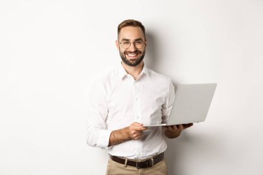 İş için. Başarılı iş adamı dizüstü bilgisayarla çalışıyor, bilgisayar kullanıyor ve gülümsüyor, beyaz arka planda duruyor.
