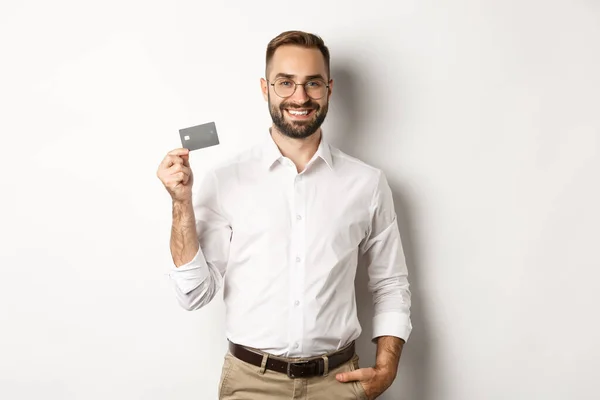 stock image Handsome businessman showing his credit card, looking satisfied, standing over white background