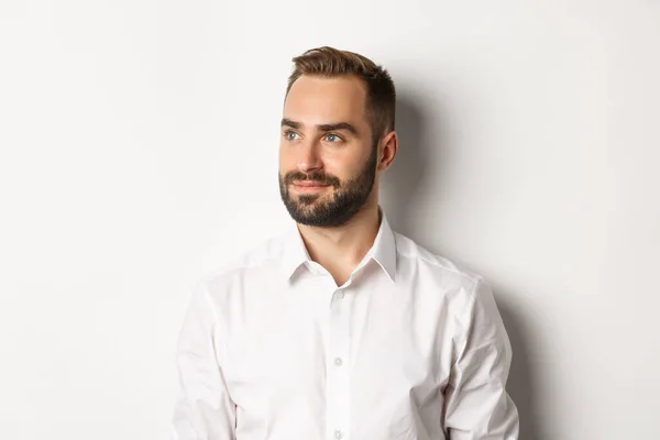 Close-up de empresário confiante em camisa branca, olhando para a esquerda e sorrindo satisfeito, de pé sobre fundo branco — Fotografia de Stock