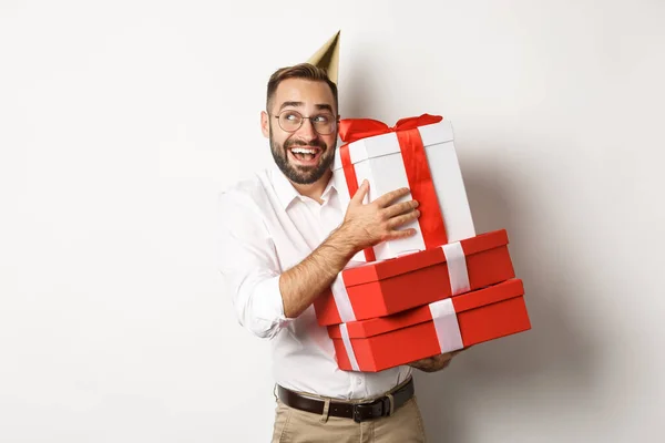 Święta i świętowanie. Podekscytowany mężczyzna mający urodziny i otrzymujący prezenty, wyglądający na szczęśliwego, stojący na białym tle — Zdjęcie stockowe