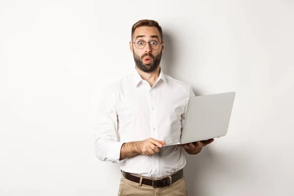 Zaken. Verrast zakenman met laptop en kijken geïnteresseerd, staan met de computer tegen een witte achtergrond — Stockfoto