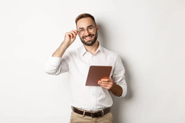 Zelfverzekerde zakenman werkt aan digitale tablet, glimlachend gelukkig, staande over witte achtergrond — Stockfoto