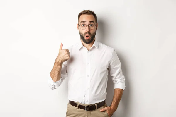 Onder de indruk jonge mannelijke ondernemer tonen duimen-up, lof iets goeds, als en eens, witte achtergrond — Stockfoto