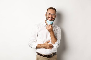 Covid-19, sosyal uzaklık ve karantina konsepti. Mutlu iş adamı maskesini çıkar ve gülümse, beyaz arka planda dur.