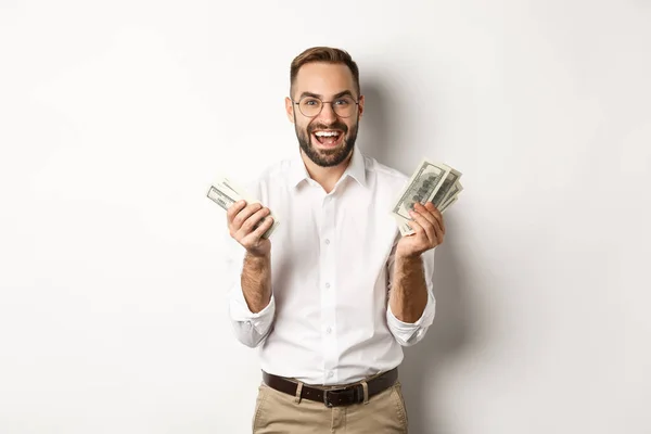 Hombre de negocios guapo y exitoso contando dinero, regocijándose y sonriendo, de pie sobre fondo blanco — Foto de Stock