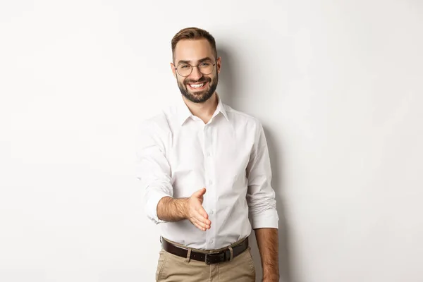 Självsäker affärsman sträcker handen för handslag, hälsning affärspartner och leende, står över vit bakgrund — Stockfoto