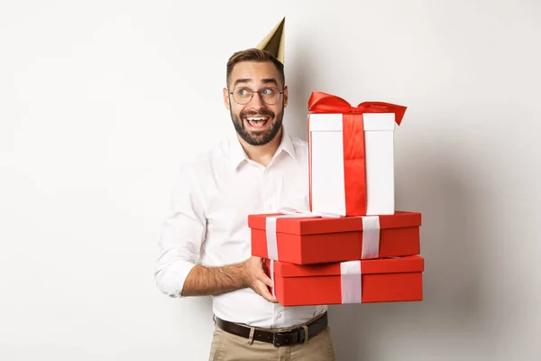 Праздники и праздники. Возбужденный человек, имеющий день рождения и получающий подарки, выглядящий счастливым, стоя на белом фоне — стоковое фото