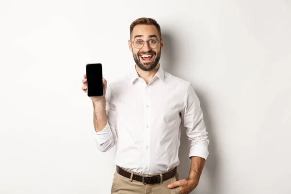 Incroyable bel homme d'affaires montrant application écran smartphone, debout sur fond blanc — Photo