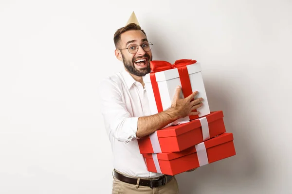 Праздники и праздники. Возбужденный человек, имеющий день рождения и получающий подарки, выглядящий счастливым, стоя на белом фоне — стоковое фото