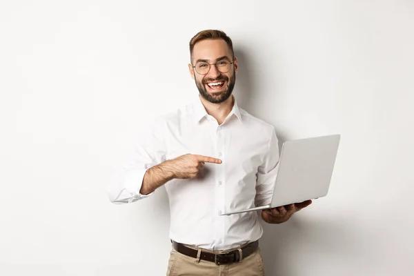 Zaken. Knappe manager in glazen werken op laptop, wijzen naar de computer en glimlachen blij, staande over witte achtergrond — Stockfoto