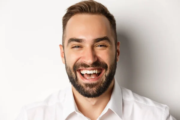 Concepto de emociones y personas. Headshot de hombre atractivo feliz riendo y sonriendo, expresar regocijo, fondo blanco —  Fotos de Stock