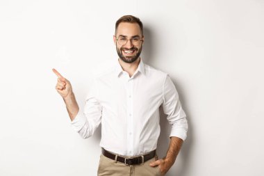 Kendine güvenen işadamı, beyaz arka planda duran şirket logosunu işaret ediyor.