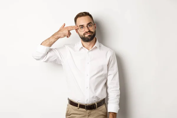 Hombre cansado haciendo disparos en la cabeza y mirando aburrido, de pie angustiado sobre fondo blanco — Foto de Stock