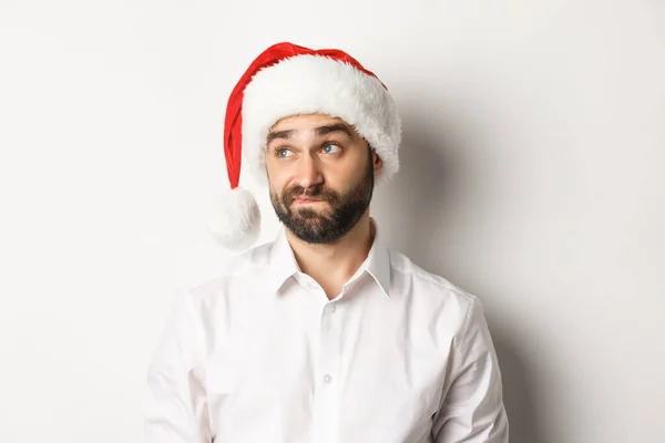Close-up de cara cético em Papai Noel olhando duvidoso esquerda, sorrindo com hesitação, fundo branco — Fotografia de Stock